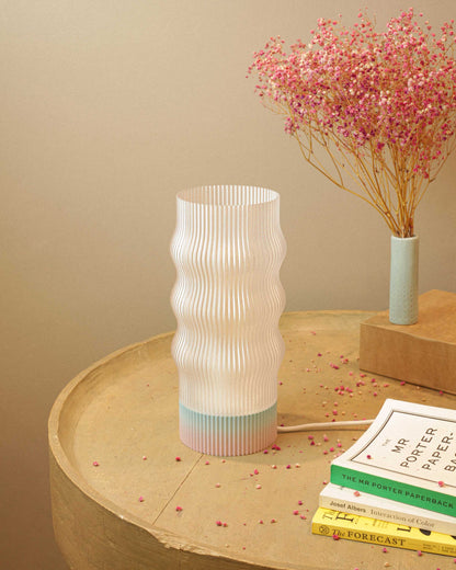 Table lamp on a wooden surface with pink flowers and books in the background